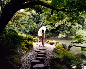 Woman with umbrella strolliing on Sawatari stepping stones, Koishikawa Koraku-en Gardens, Tokyo, Japan